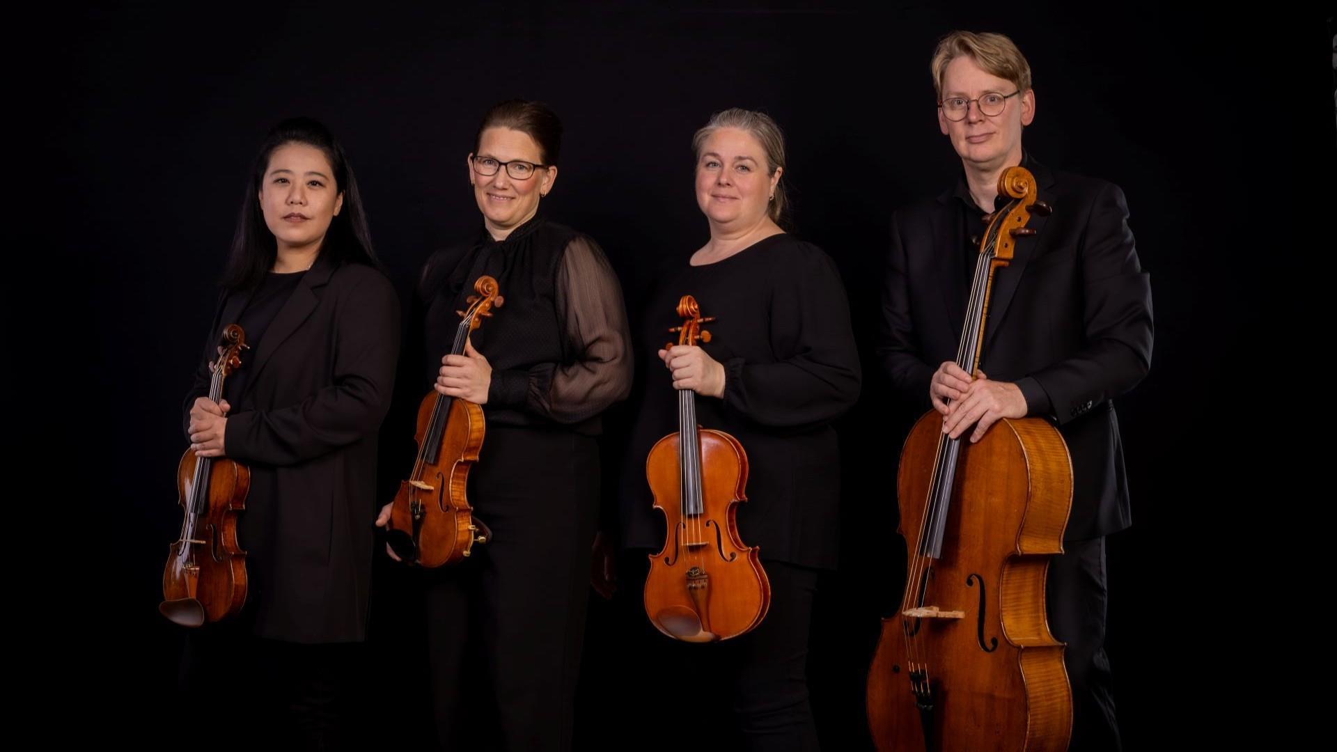 Strykekvartettens fire medlemmer i svarte klær med instrumenter i hendene.